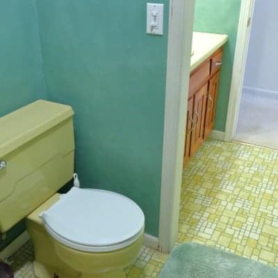 Harvest gold toilet with white lid in green bathroom remodel project