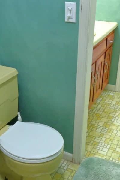 Harvest gold toilet with white lid in green bathroom remodel project