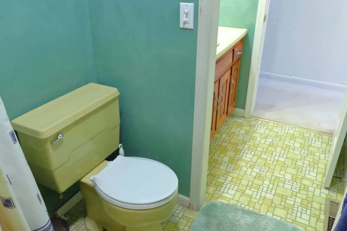 Harvest gold toilet with white lid in green bathroom remodel project