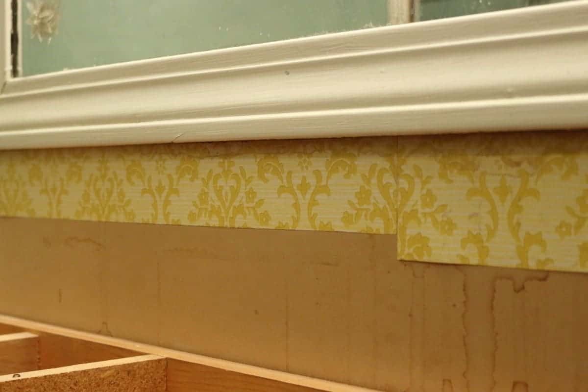 Photo of old yellow wallpaper and framed mirror before a DIY bathroom mirror frame project.