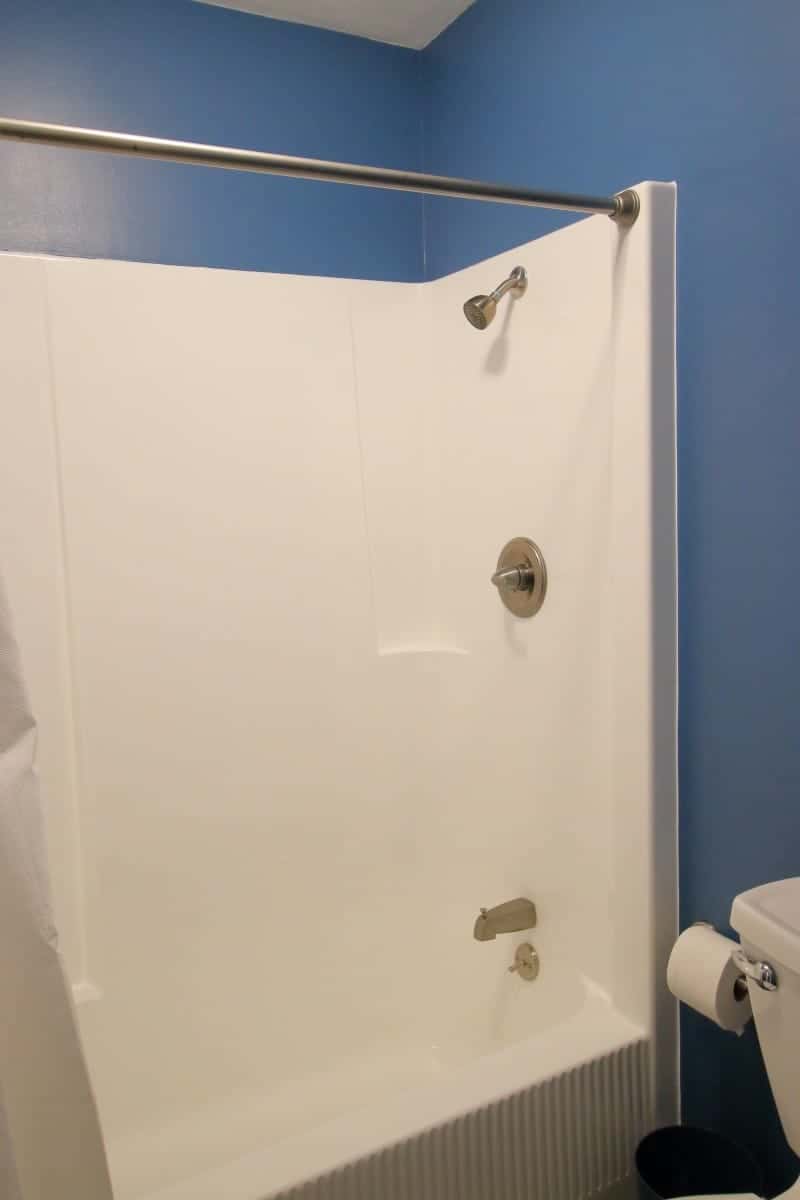 1970s bathroom updated with refinished white tub/shower unit and dark blue walls