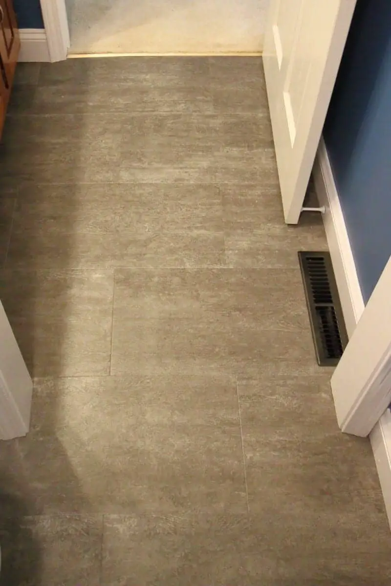 Dark grey luxury vinyl tile, white woodwork and dark blue walls in a bathroom remodel