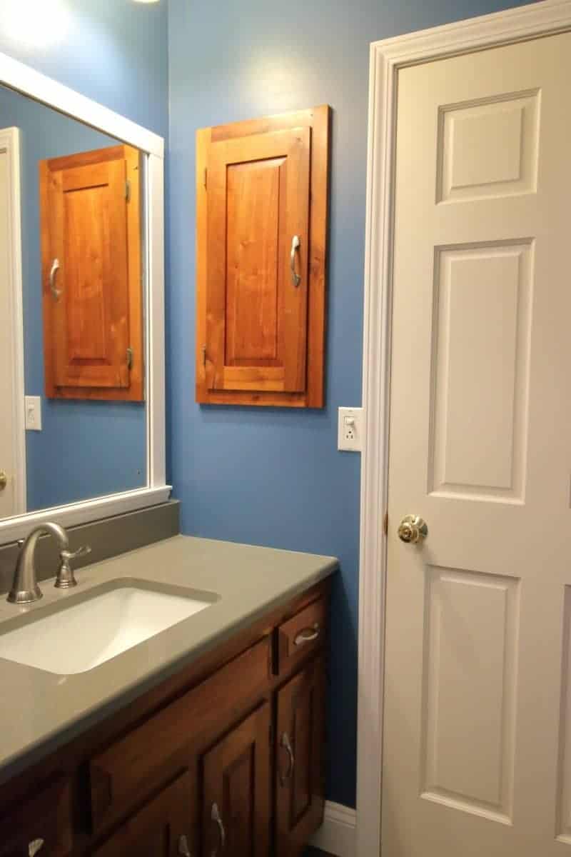 Remodeling a 1970s bathroom - dark blue walls, white door, quartz countertop, and a hickory vanity cabinet and medicine cabinet