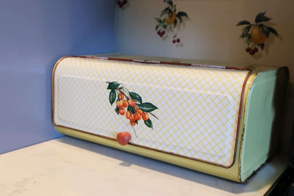 Vintage yellow bread box with cherries on the front.