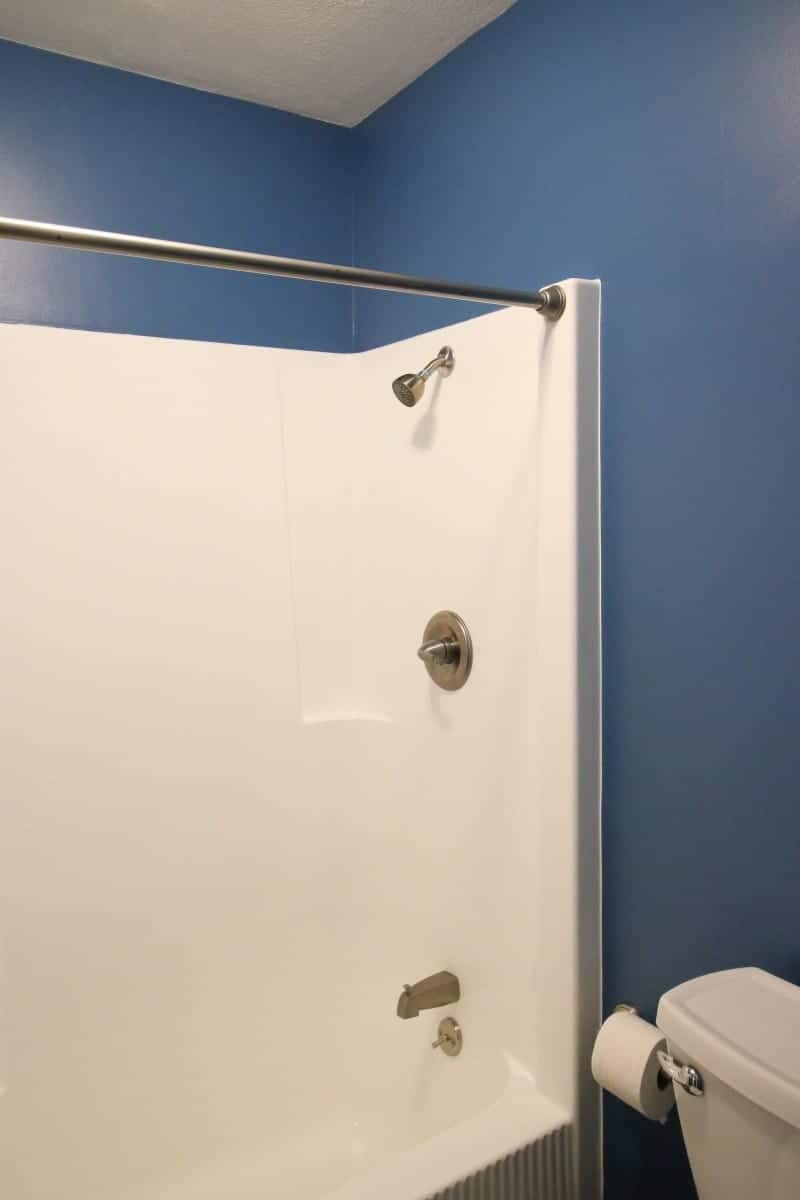 White tub and dark blue walls in after picture of bathroom remodel