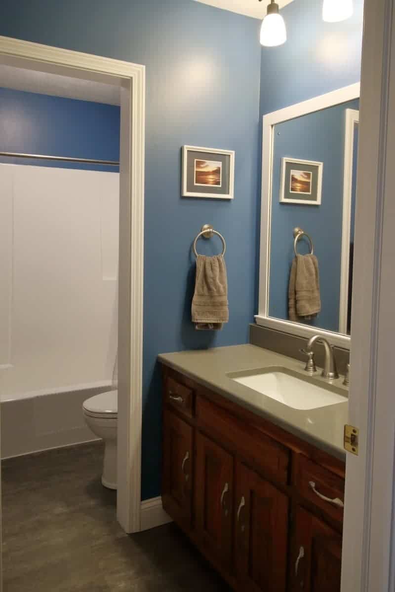 Bathroom remodel after photo of dark blue walls, white trim, dark grey quartz countertop