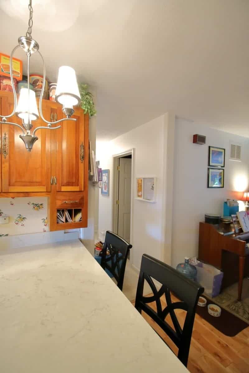 White quartz countertop and breakfast bar with black chairs in kitchen remodel