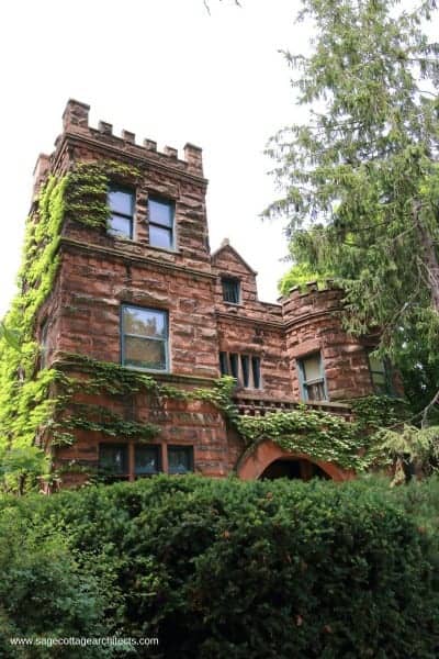 Rough cut exterior stone house with corner tower and battlements, typical of Richardsonian Romanesque homes.