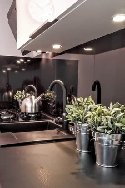 Compact black kitchen with sage plants growing in galvanized buckets.