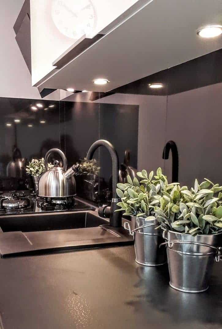 Compact black kitchen with sage plants growing in galvanized buckets.