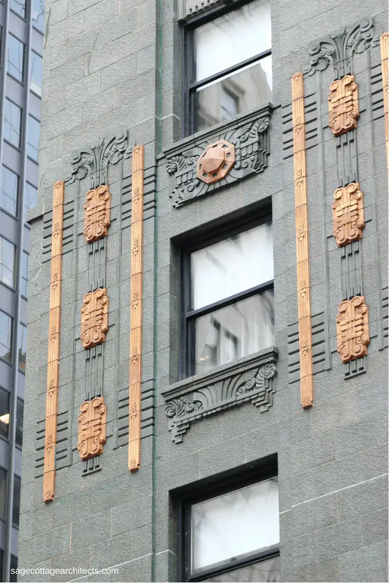 Art Deco bronze decorations on a dark green/grey terra cotta wall