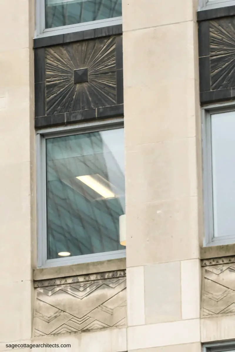 Black Art Deco sunburst spandrel panel above a window with carved chevron limestone panel underneath