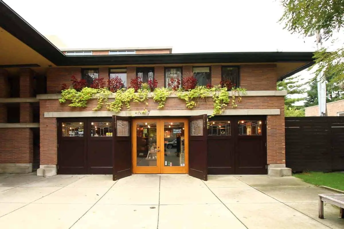 Garage of the Robie House - dark brown doors, red brick, limestone banding, and low roof.