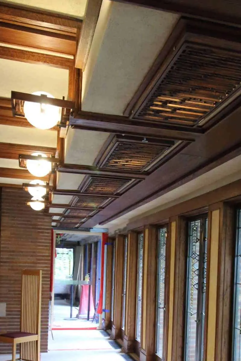 Interior of Prairie style home - oak ceiling beams, cream walls, and a wall of windows. 