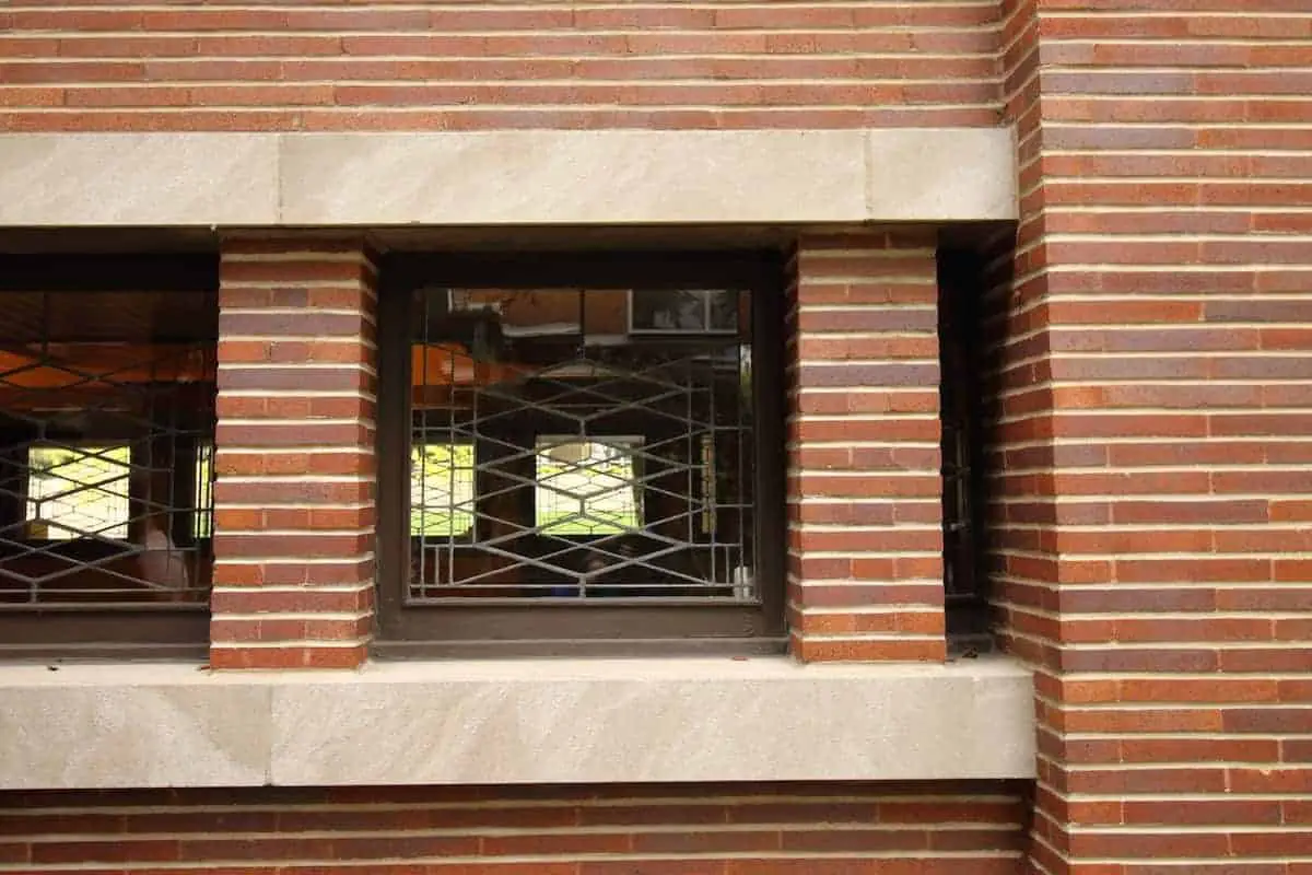 Close-up of Prairie Style home exterior: red brick, white limestone banding, and stained glass windows.