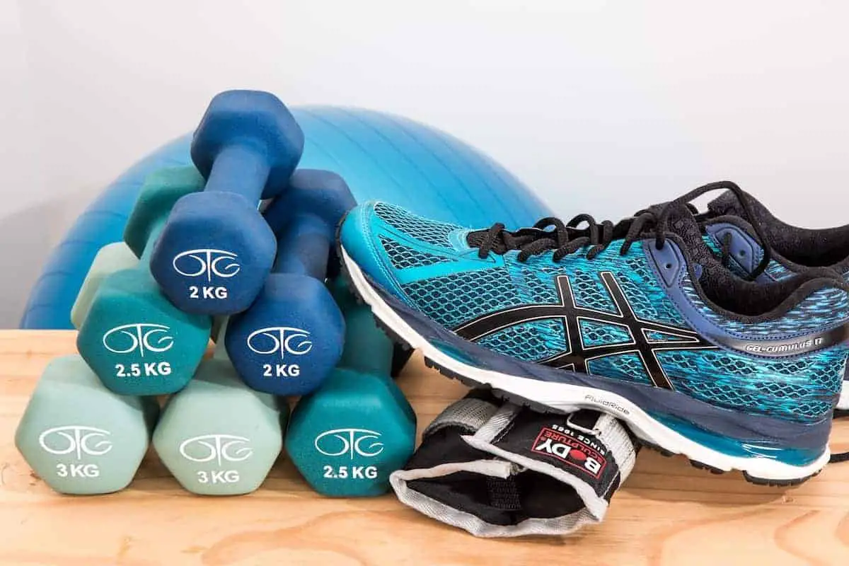 Photo of blue tennis shoe, dumbbells and blue workout ball that will be part of your best home gym.