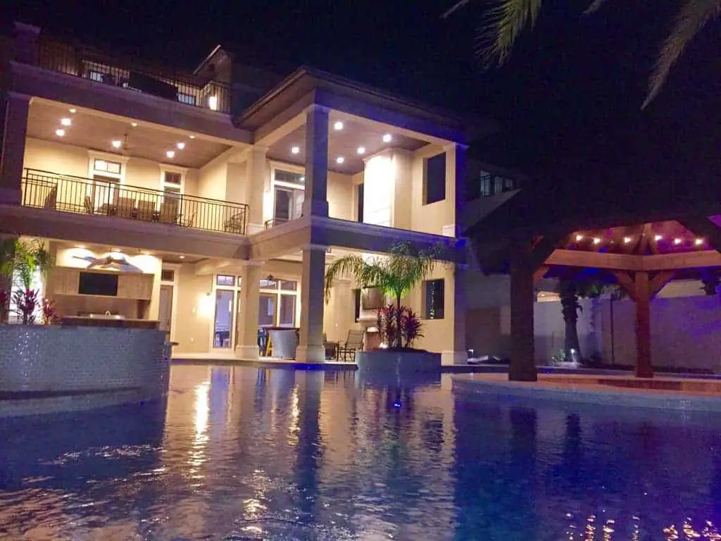 Photo of a large beach vacation home with a pool at night.