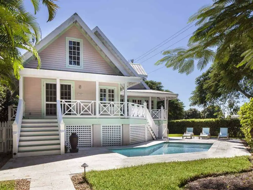 Photo of a Key West style beach vacation home with pink siding and white trim. 