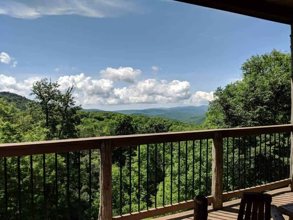 Picture of a ski vacation home rental in the summertime, looking over a porch railing at the Smoky Mountains. 