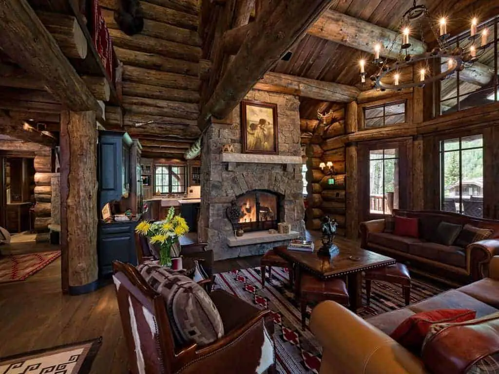 Photo of the interior of a ski vacation lodge home with exposed logs and stone fireplace.