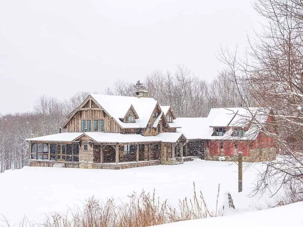 Photo os a farmhouse, that is perfect for a ski vacation, in the snow. 