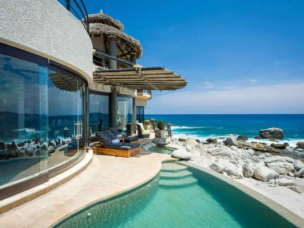 Photo of a glass and stucco beach vacation home with pool.