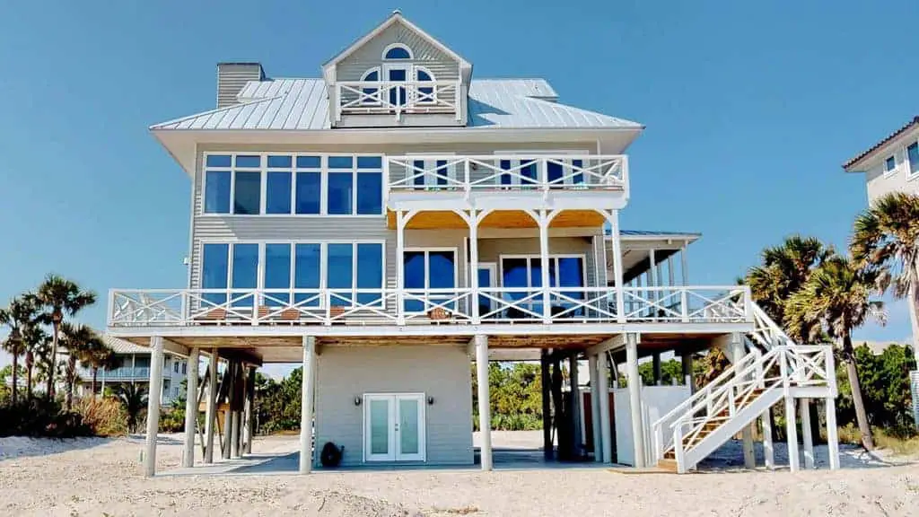 Photo of large beach vacation home, with white porches, on the gulf coast home. 