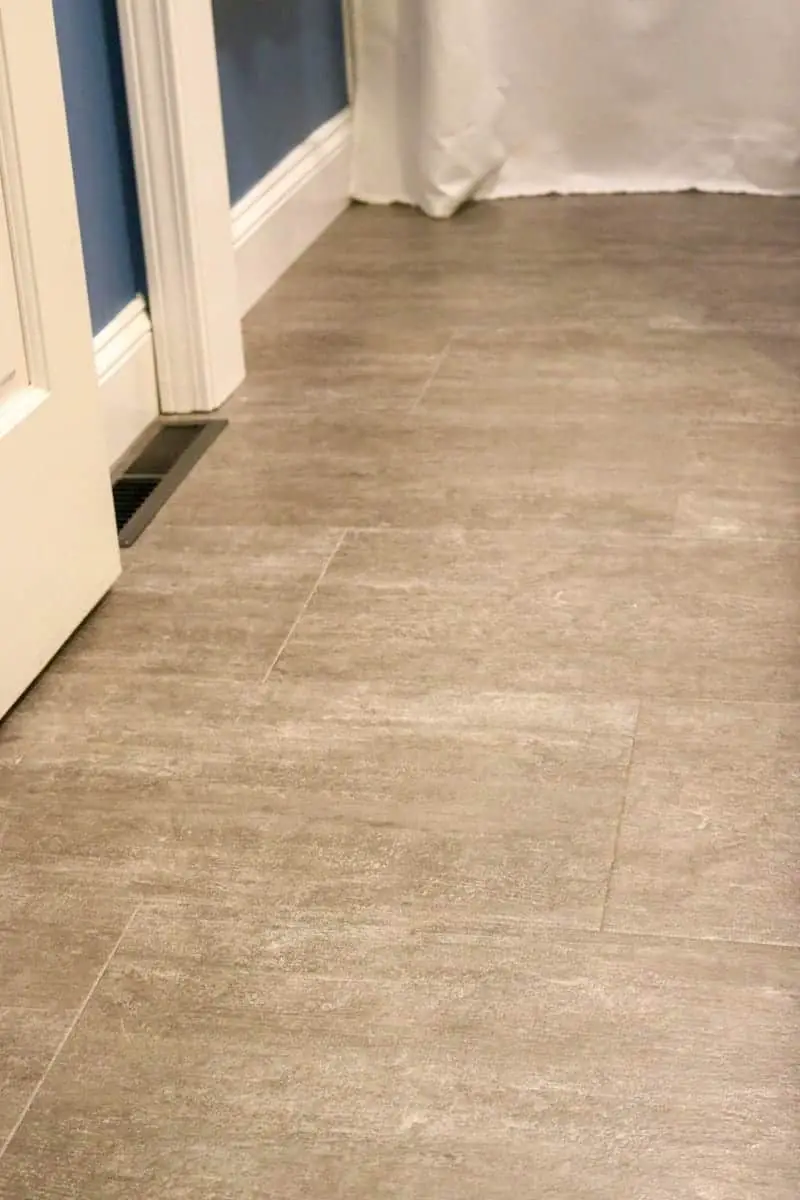 Photo of grey luxury vinyl tile flooring, dark blue walls and white trim.