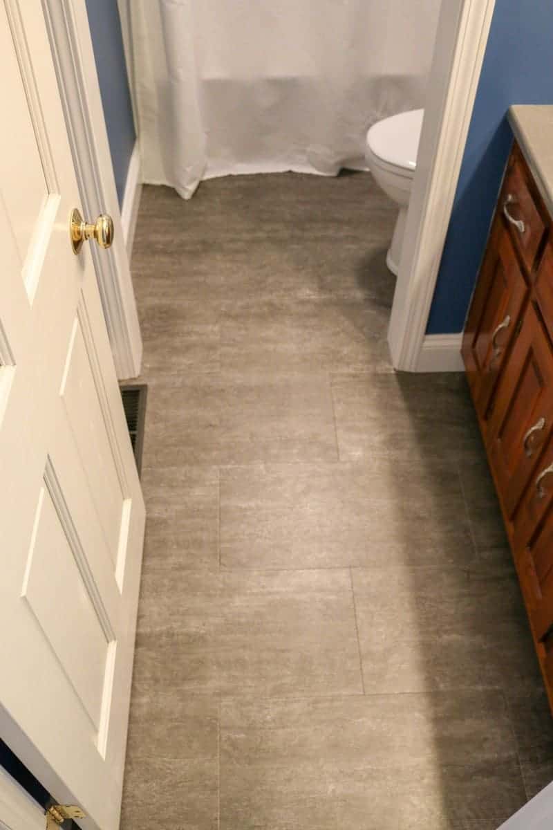 Photo of dark blue bathroom with grey luxury vinyl tile flooring