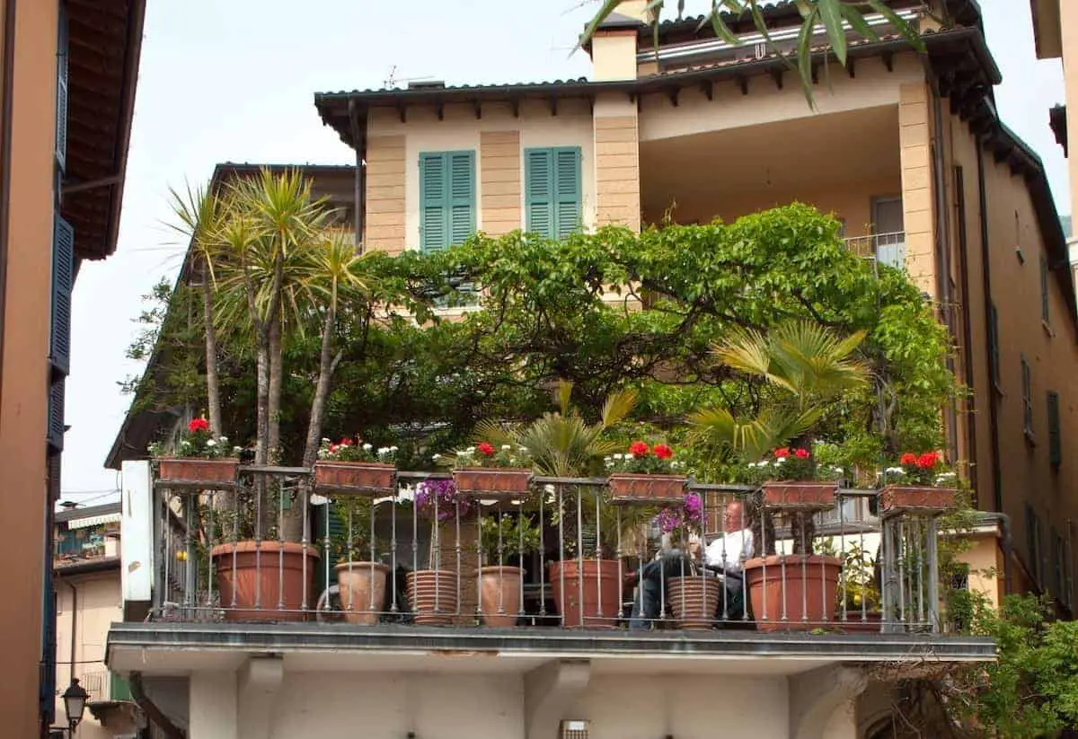 Photo of a man sitting on a balcony, that can inspire many small balcony ideas.