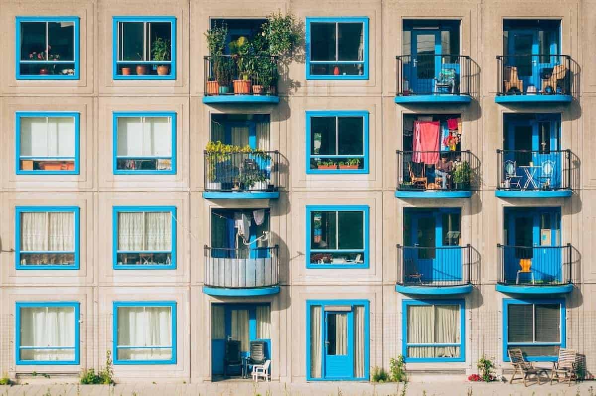 Photo of cream colored apartment building with bright blue window trim and small balcony ideas.