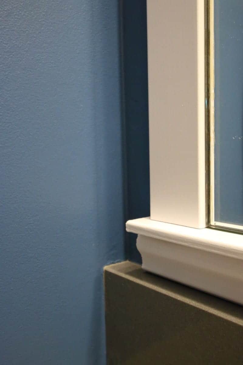 Photo closeup of white wood DIY bathroom mirror frame project.