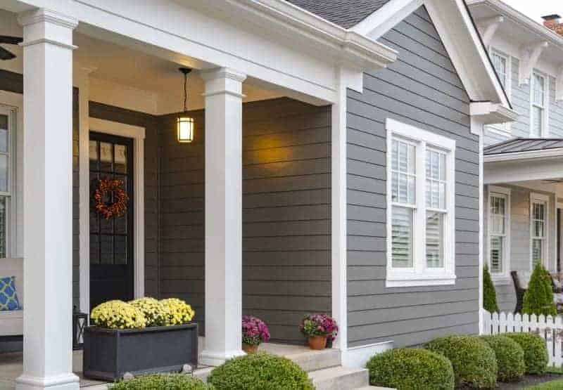 Photo of house with dark grey siding and white columns on porch