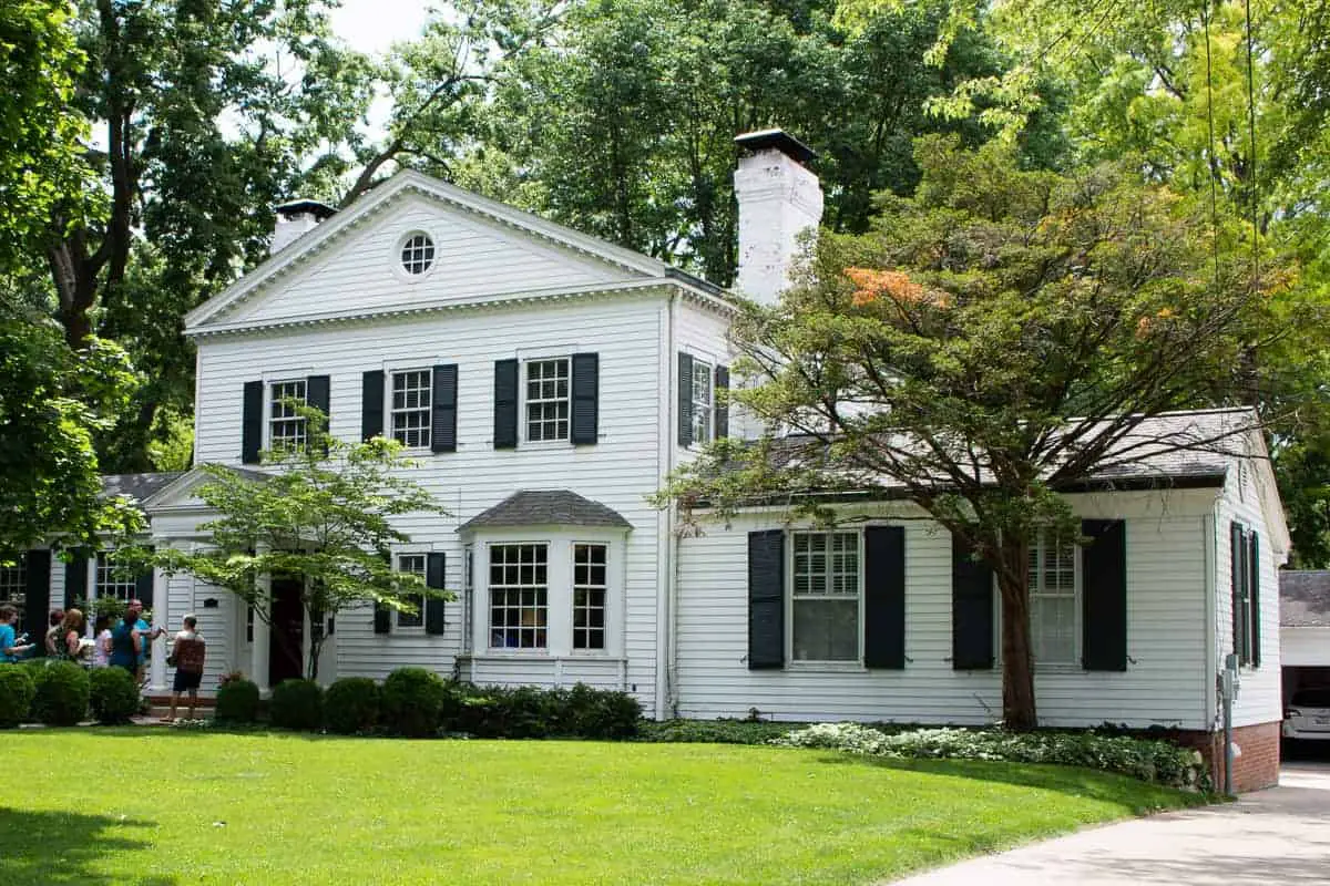 Photo of traditional home with white siding and black window shutters on old house tour.