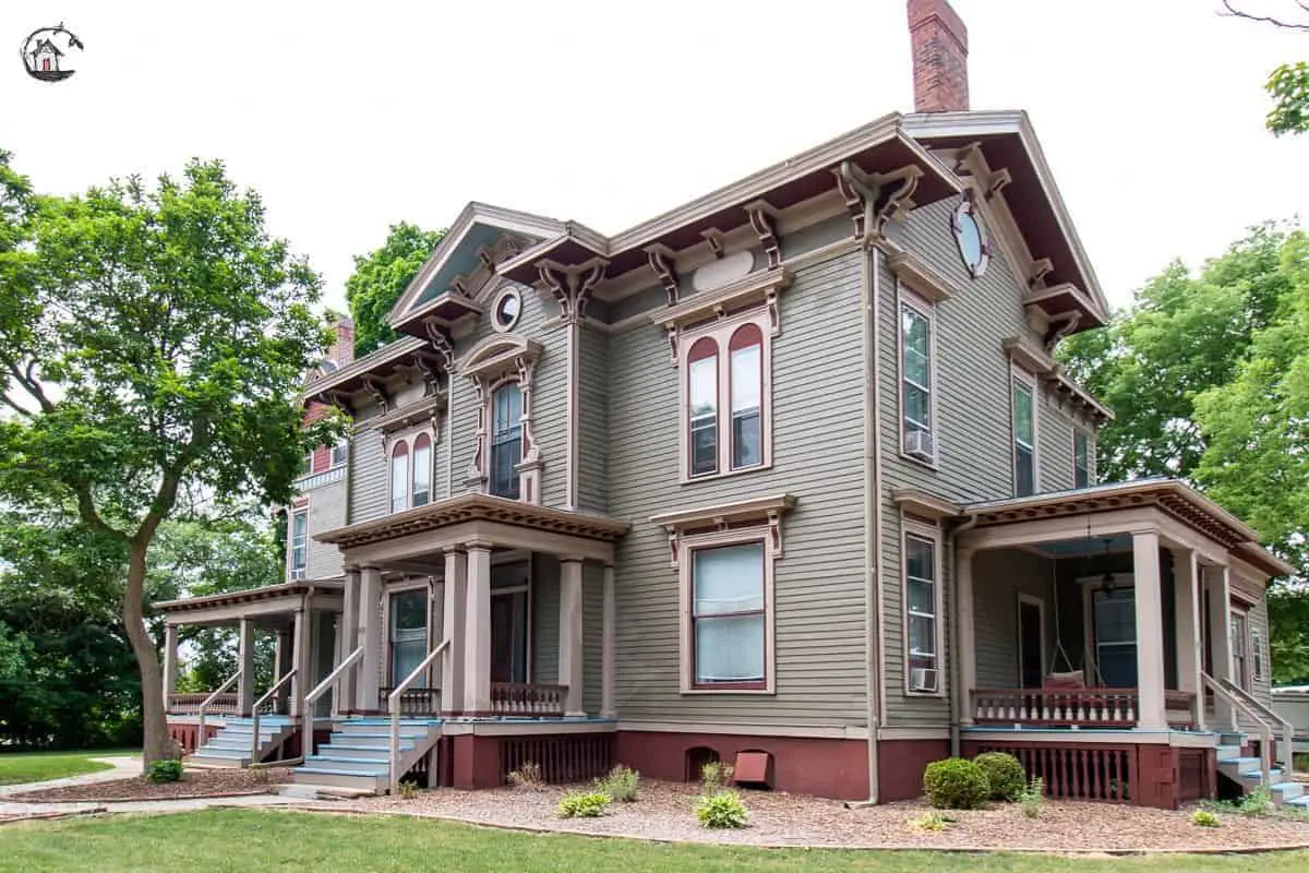 Photo of dark green Victorian home with red and cream details, from a collection of old houses. 