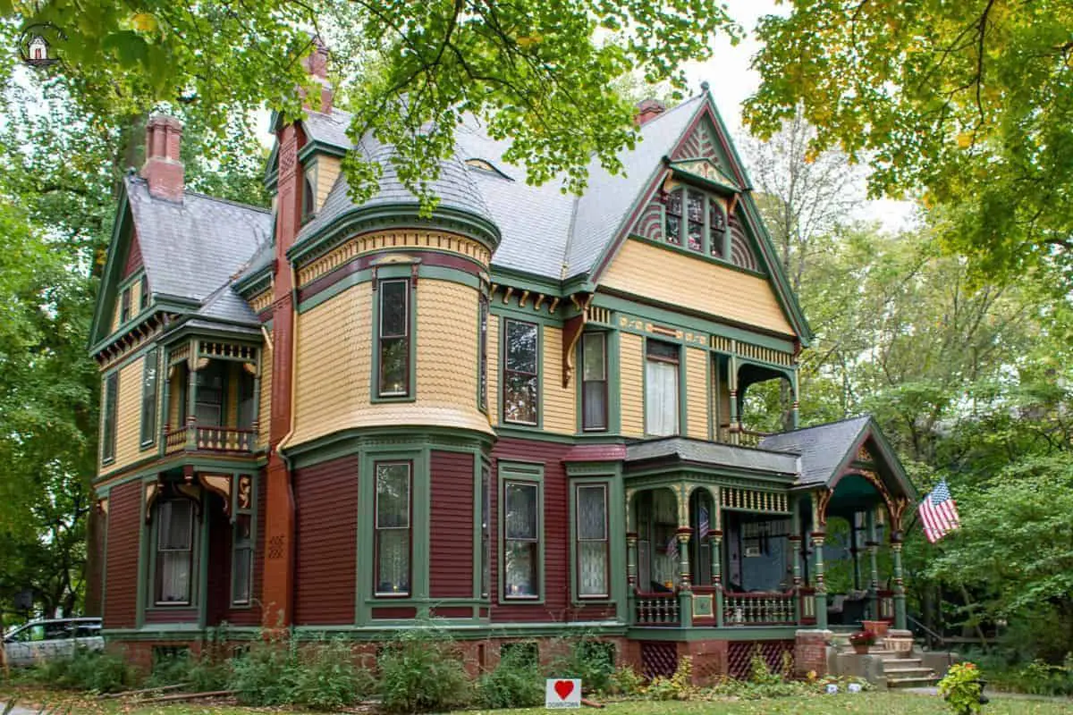Photo of Victorian home with yellow, green, and dark red color scheme. 