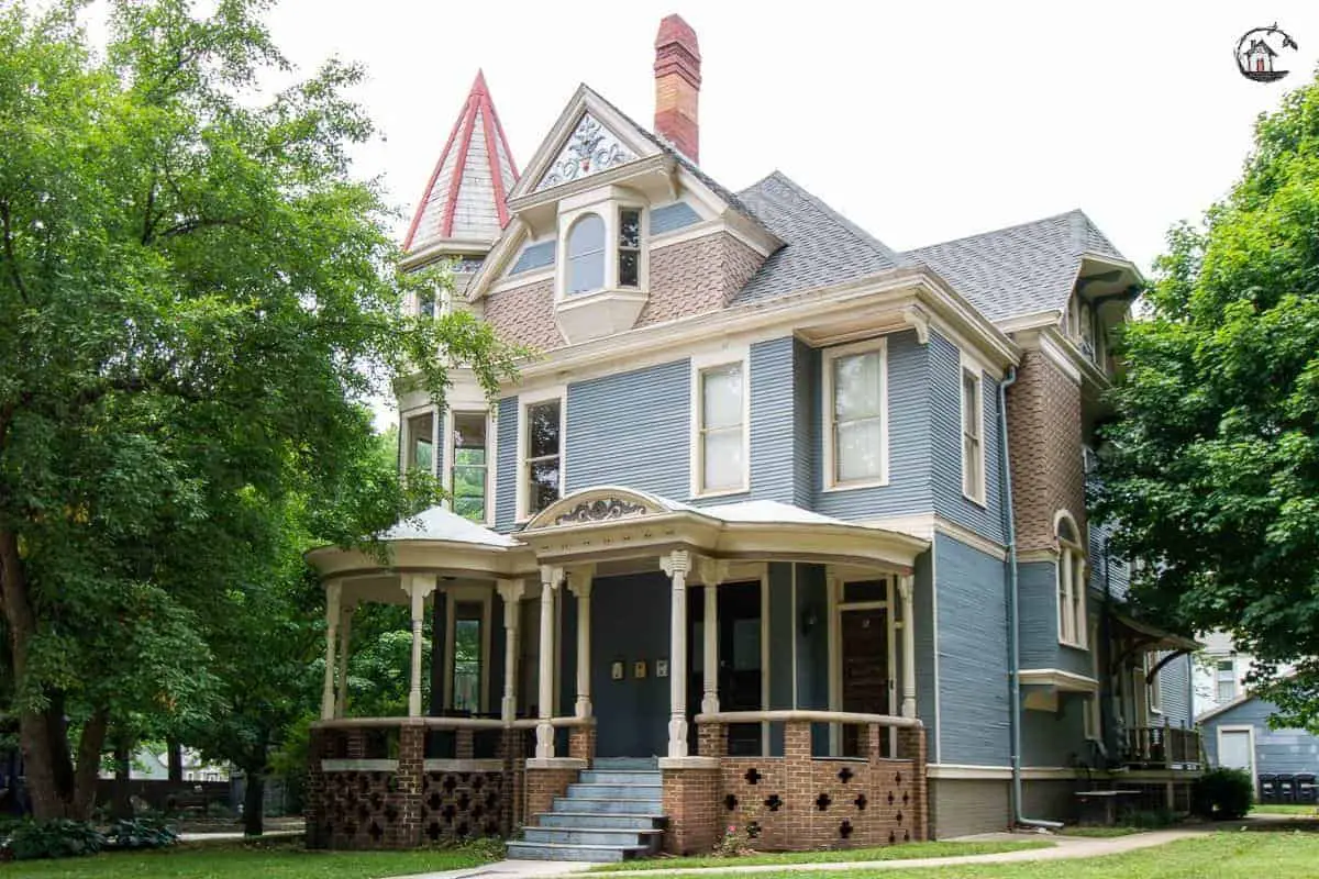 Photo of light blue Victorian home with large front porch in a neighborhood of old houses. 