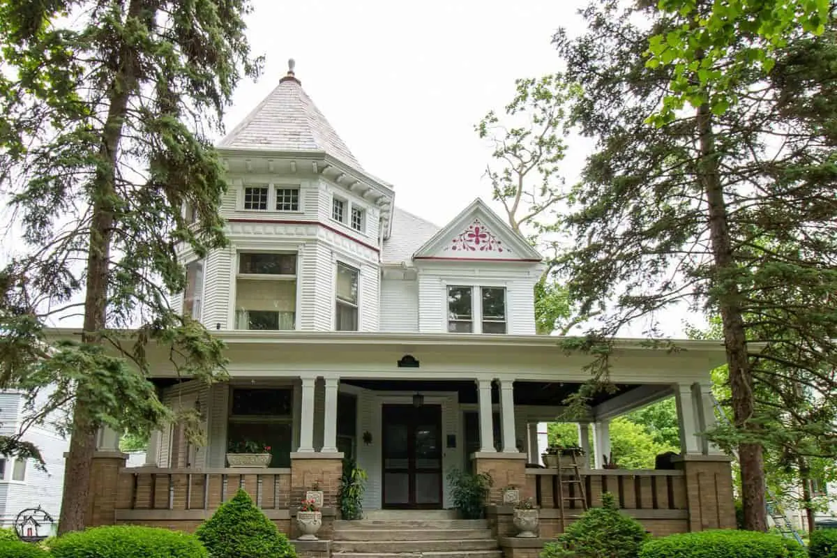 Photo of a large white Victorian home, in a neighborhood of old houses. 