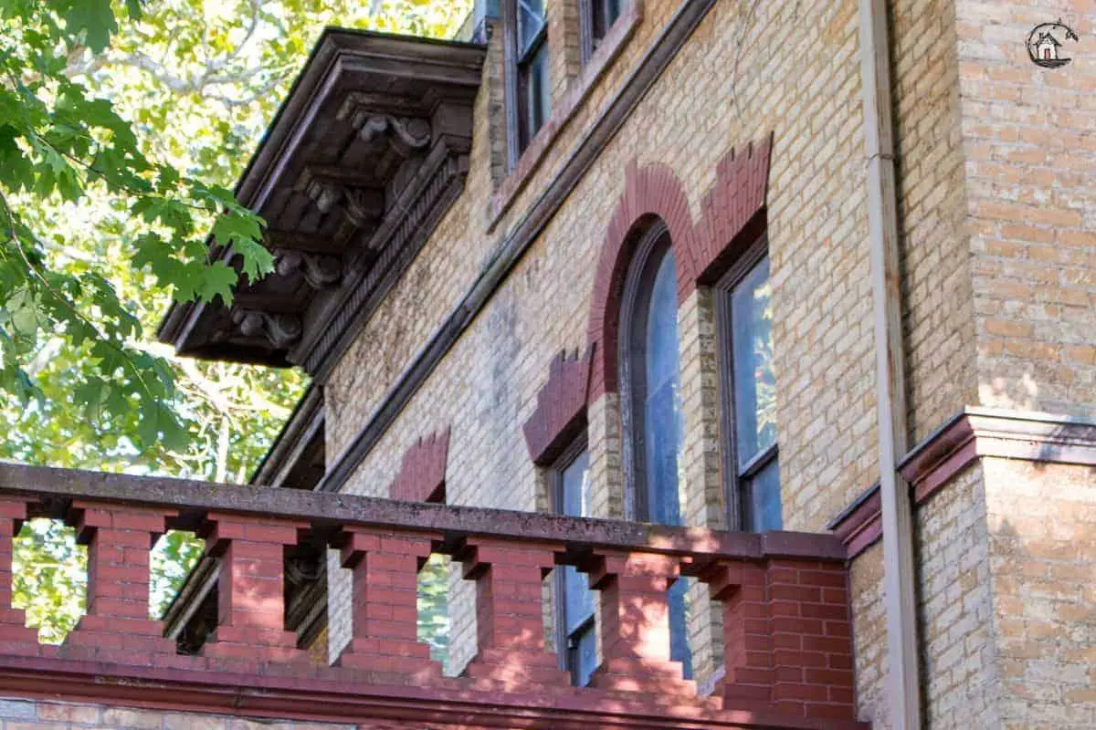 Photo of red brick balcony railing, and Palladian window on the front of the Vrooman Mansion. 