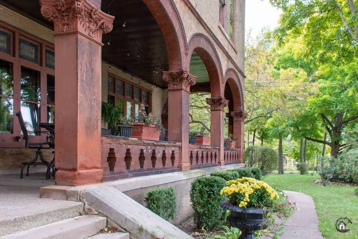 Photo of red brick arches, with ornate column capitals, on the side porch of the Vrooman Mansion. 