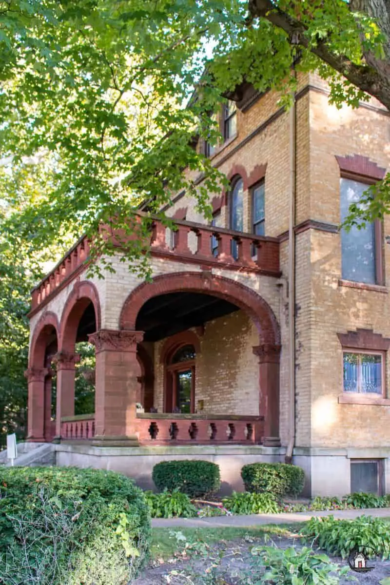 Photo of the entry porch of the Vrooman Mansion with red brick arched openings and railings. 