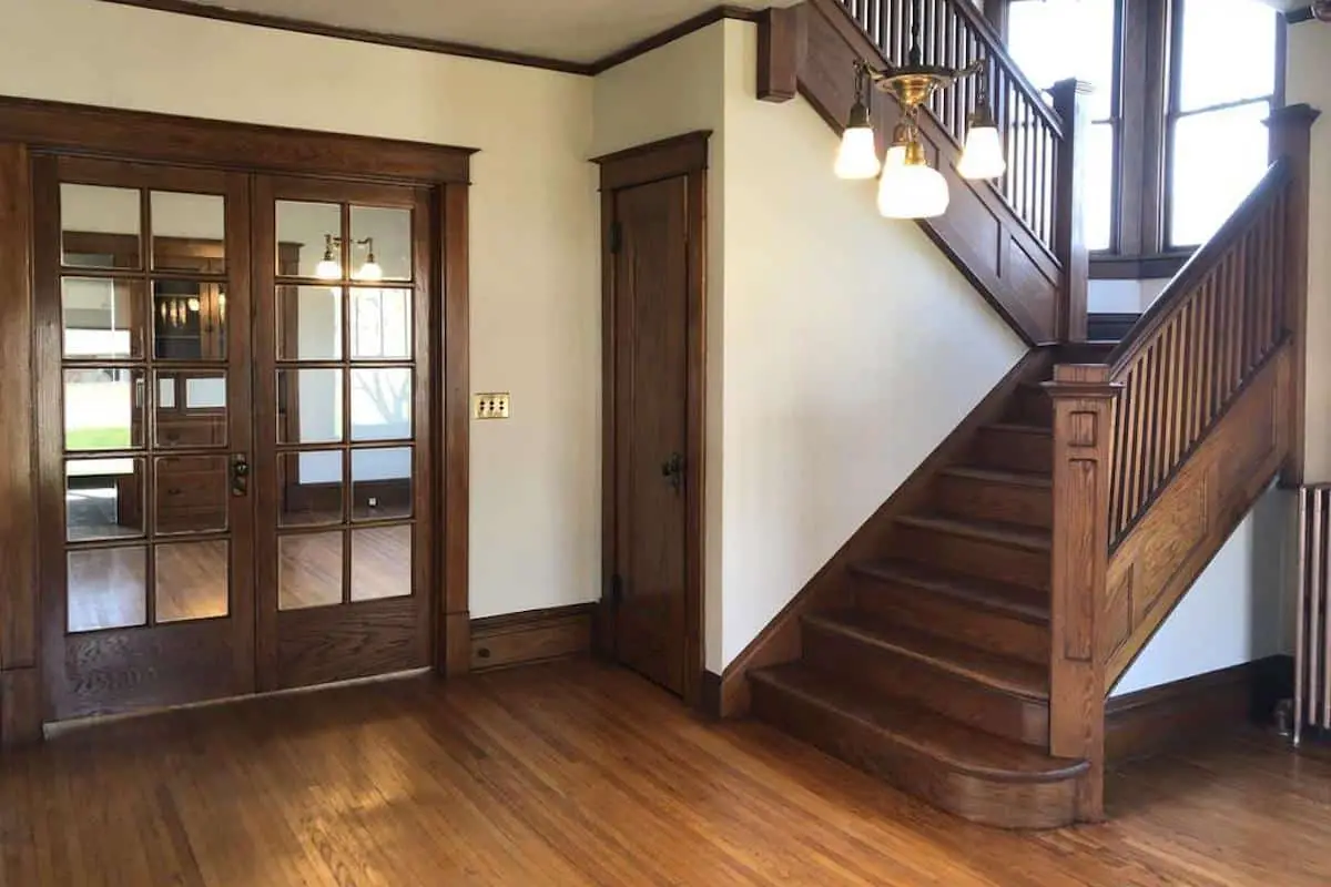 Photo of an American Foursquare home interior with oak stairs and French doors. 