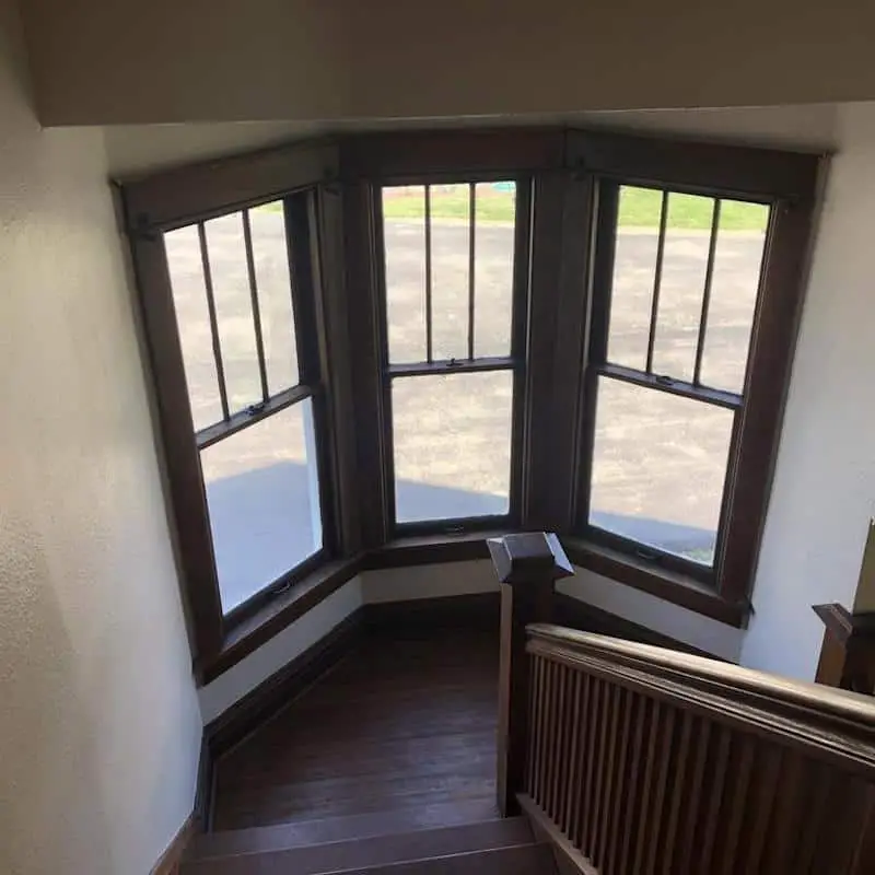 Photo of a stair landing with three windows in an American Foursquare home. 