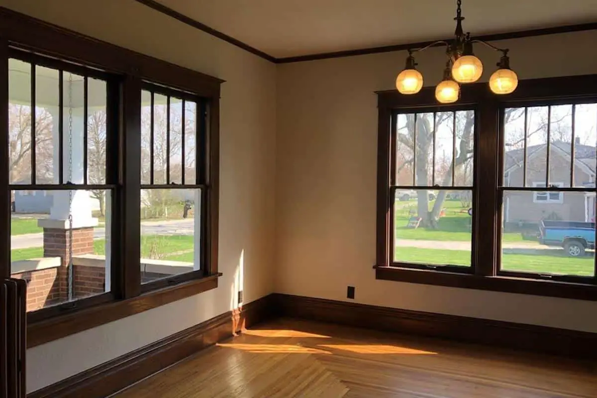 Photo of interior of an American Foursquare style home with large windows on two walls. 