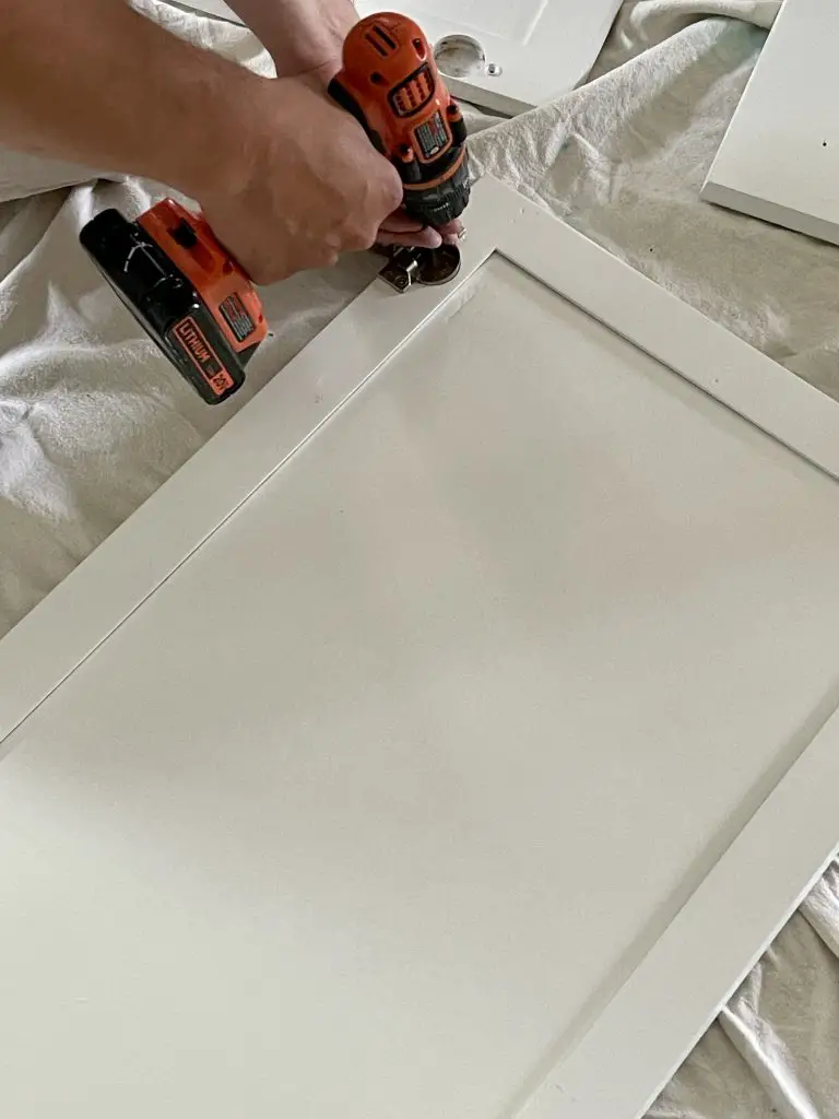 drill attaching hardware to white cabinet door