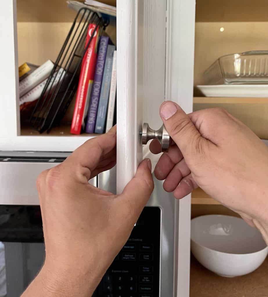hands replacing hardware on cabinet door