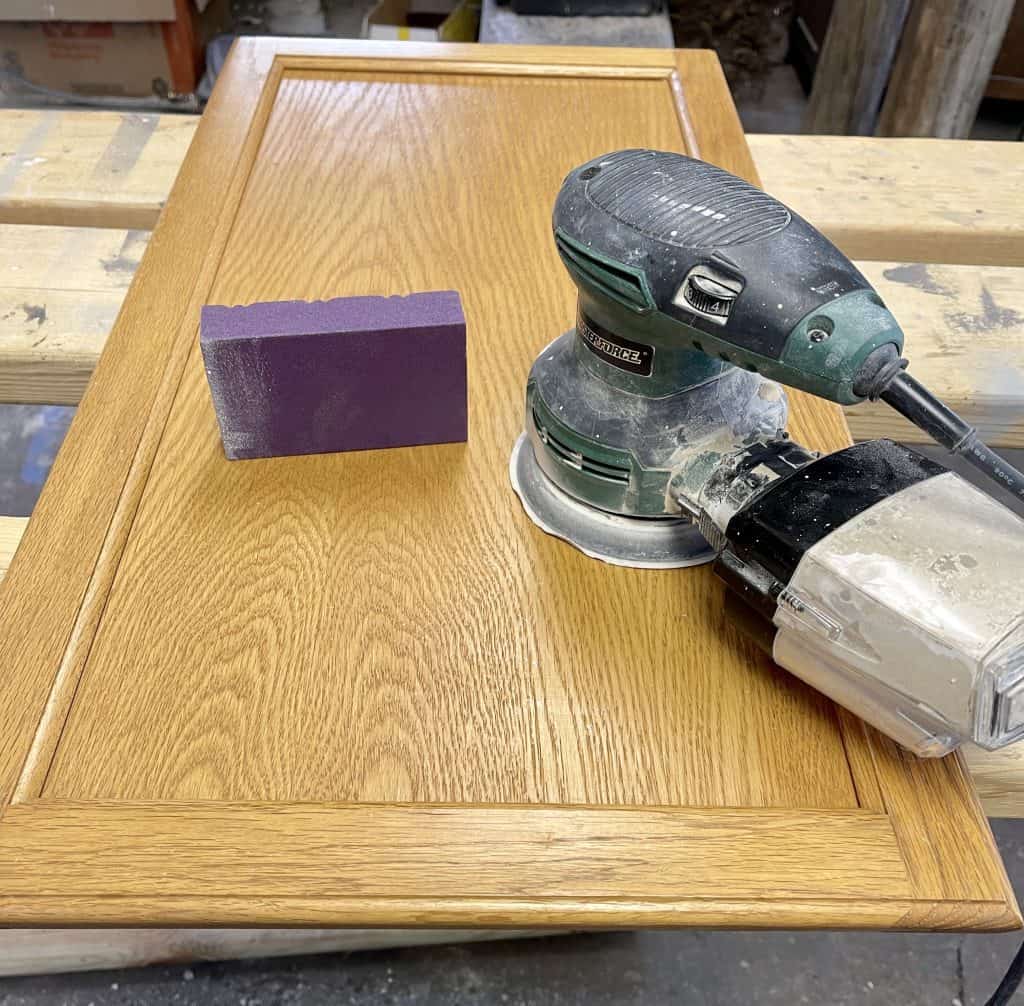 How to Paint Kitchen Cabinets that are Stained 13 orbital sander and sandpaper on cabinet door