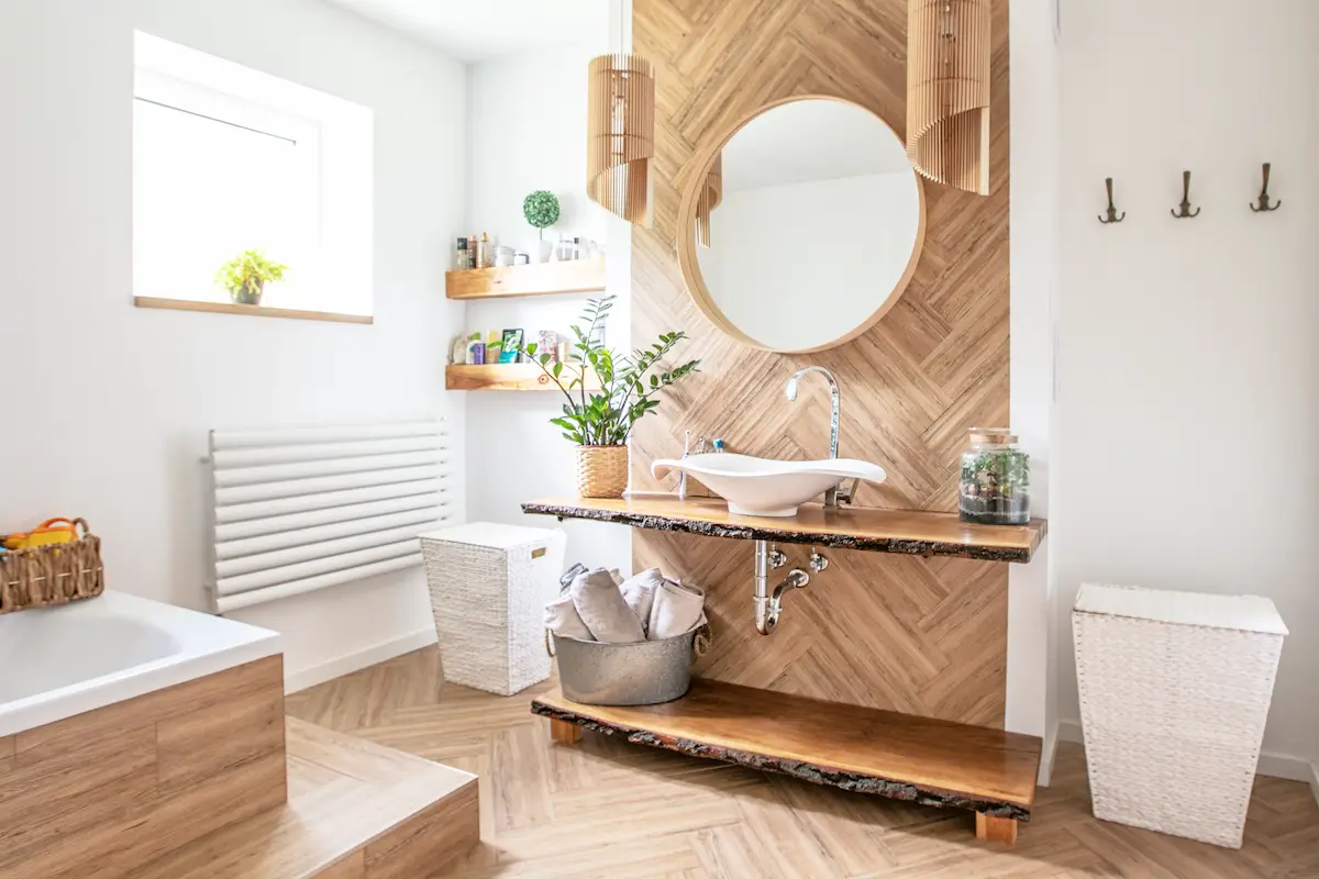 White sink on wood counter with a round mirror hanging above it. Bathroom interior.