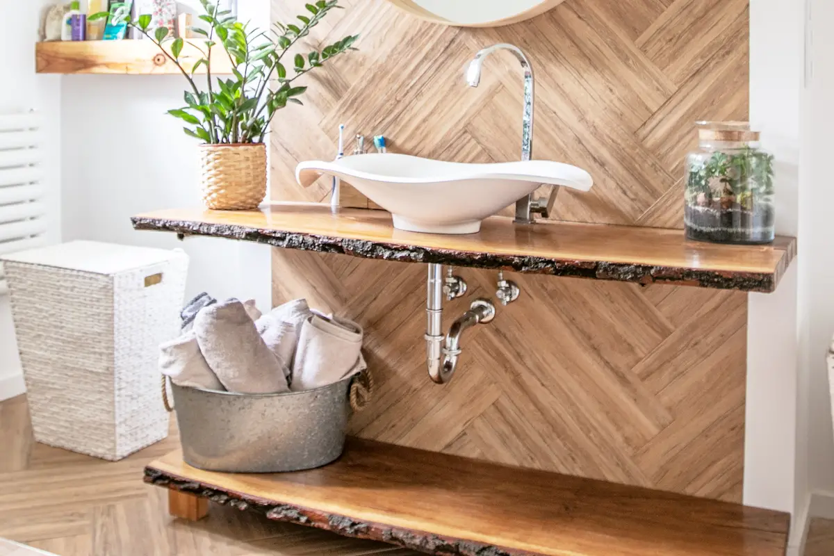 White sink on wood counter with a round mirror hanging above it. Bathroom interior.